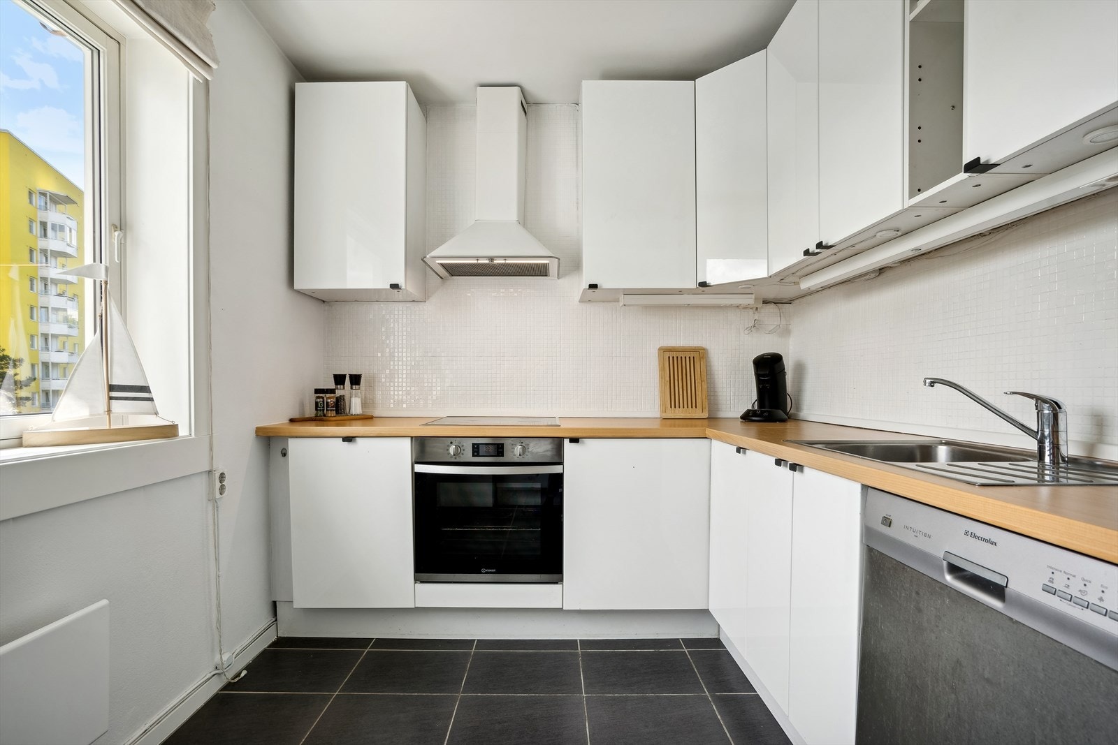 Moderne Ikea kjøkkeninnredning. Glatte, høyglans fronter. Laminat benkeplate med nedfelt kum i rustfritt stål. Galleribilde
