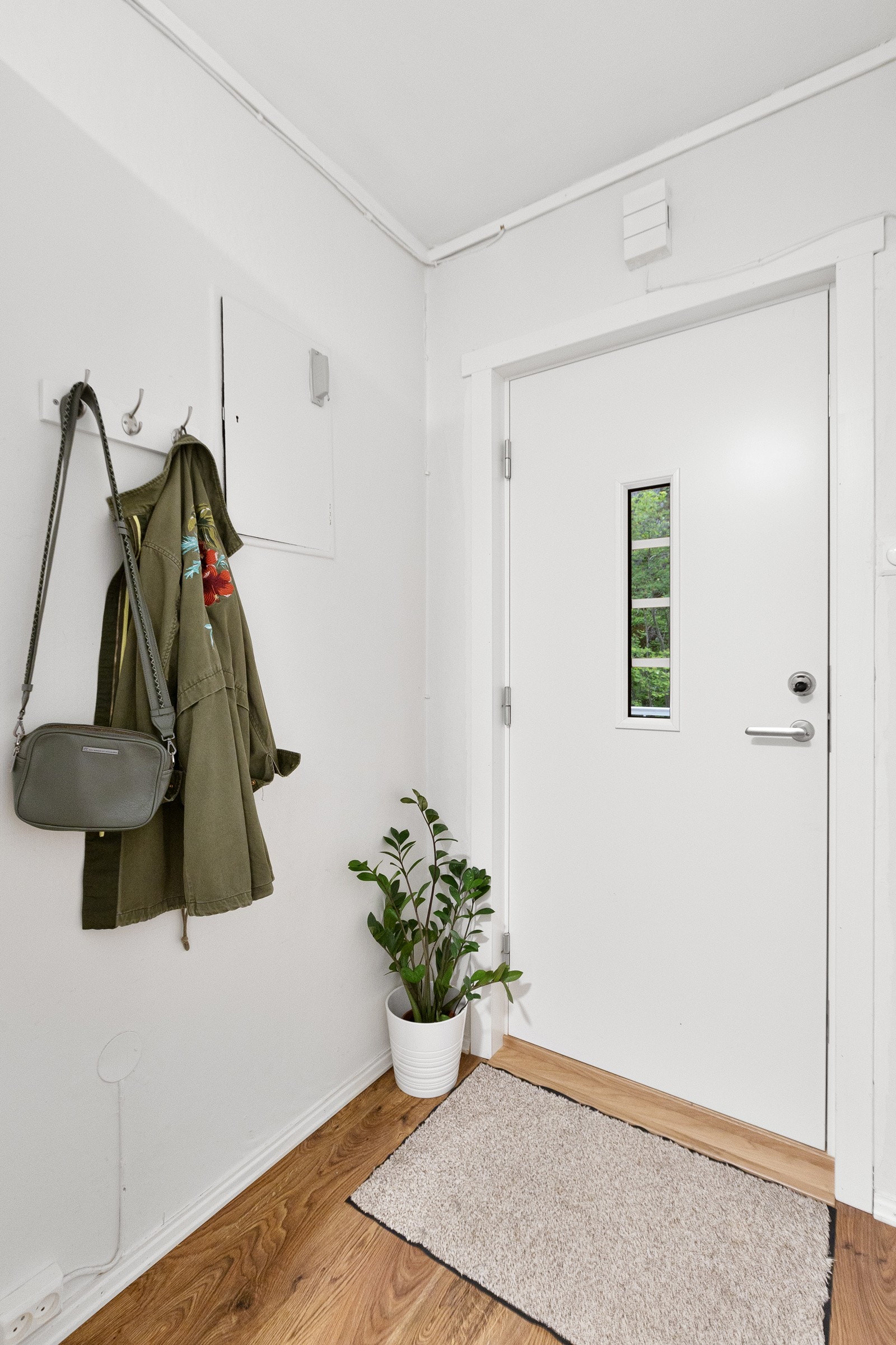 Leiligheten har en innbydende entré med laminat på gulv og malte overflater. Galleribilde