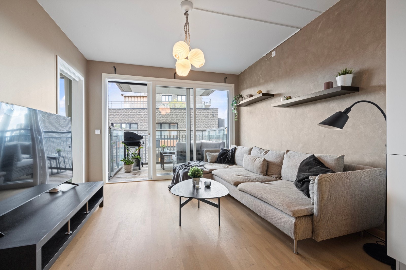 De malte veggene i beige gir en varm og innbydende følelse, mens veggen ved sofaen er dekorert med stilfull kalkmaling Galleribilde