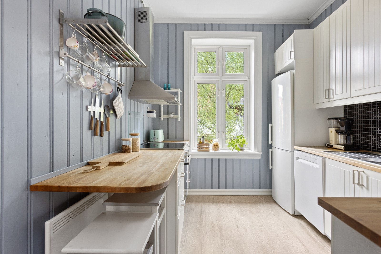 Kjøkkenet har god standard med lys enstavs laminat på gulv og panel på veggene malt i en nydelig lys blåfarge. Galleribilde