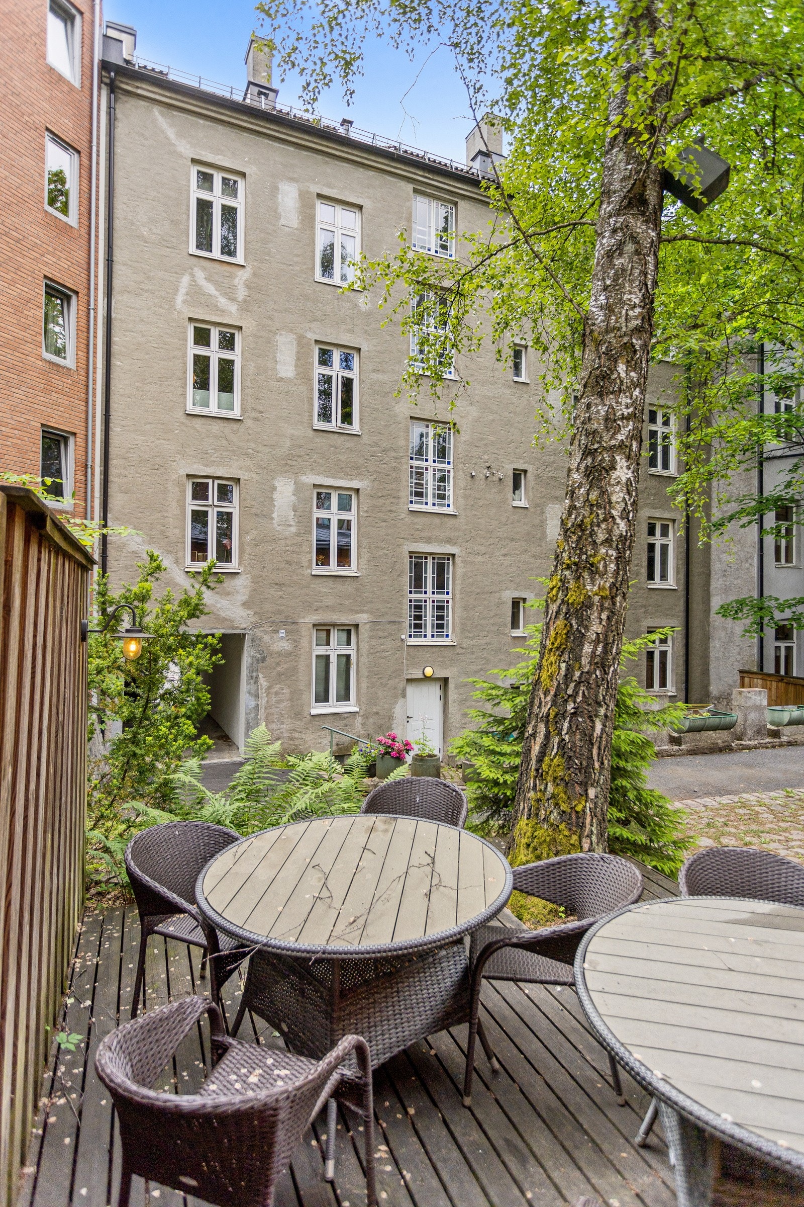Bakgården er opparbeidet med terrasseplatting med sittegrupper, plenarealer, diverse beplantning og busker/trær. Galleribilde
