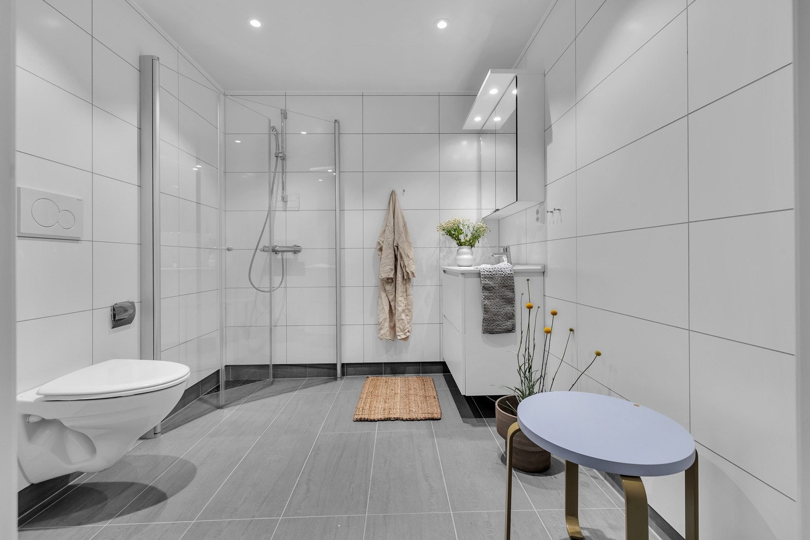 Badet er flislagt på gulv og vegger, har innfellbare glassdører i dusjsonen, innfelt belysning i tak m.m. Galleribilde