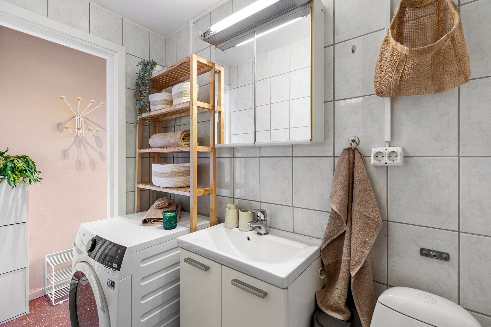 Flislagt bad med varmekabler, dusjnisje, veggmontert servantskap og gulvstående klosett Galleribilde