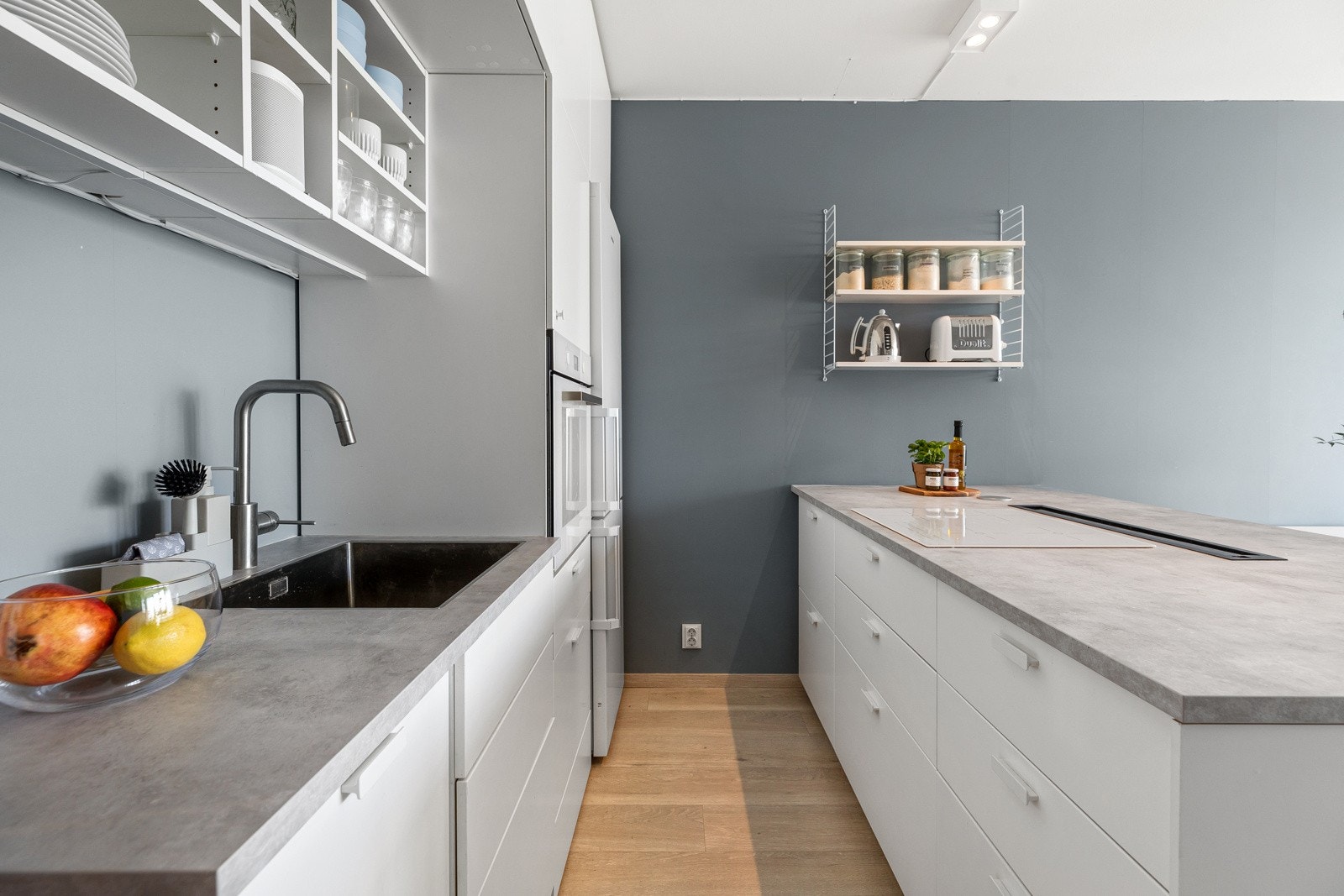 Videre er det integrerte hvitevarer fra Ikea som oppvaskmaskin (smal), stekeovn i høyskap og platetopp i kjøkkenøy samt integrert kjøkkenavtrekk i benkeplate med kullfilter fra Elica. Galleribilde