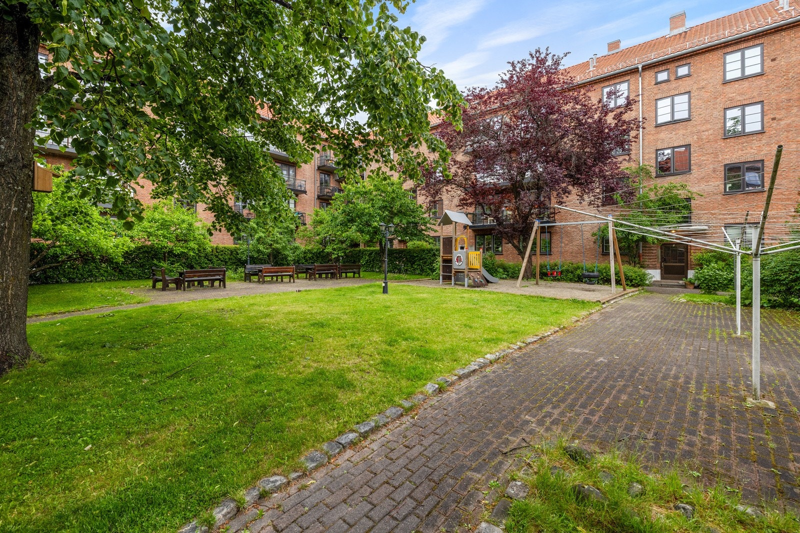 Stor og solrik bakgård med flere sittegrupper, idyllisk beplantning, grill og lekestativ. Galleribilde