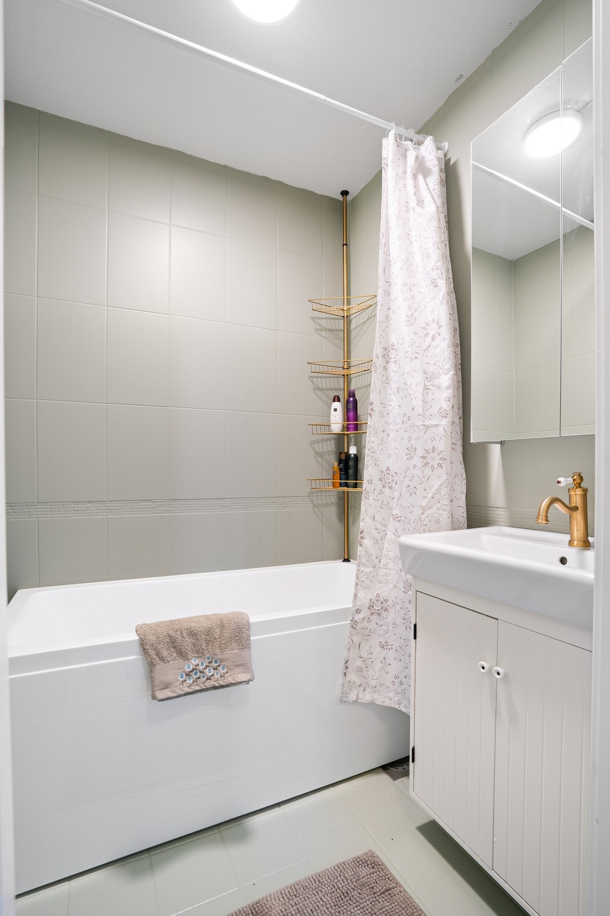 Pent flislagt bad utstyrt med badekar, mekanisk avtrekk og servant i skap. Galleribilde