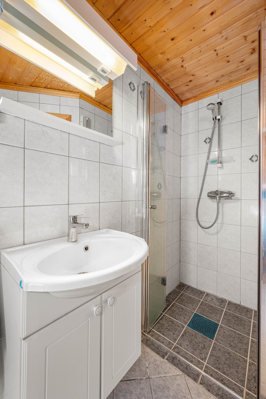 Badet er innredet med dusjhjørne og vegghengt toalett. Galleribilde