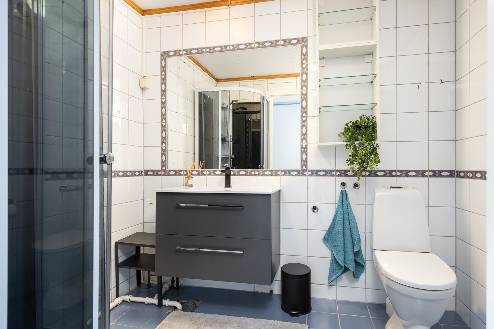 Badet er på 4,3m² og fremstår som pent med flislagte vegger og gulv. Rommet ble oppusset på slutten av 90-tallet og har dusjkabinett, gulvmontert toalett og innredning med servant. Galleribilde