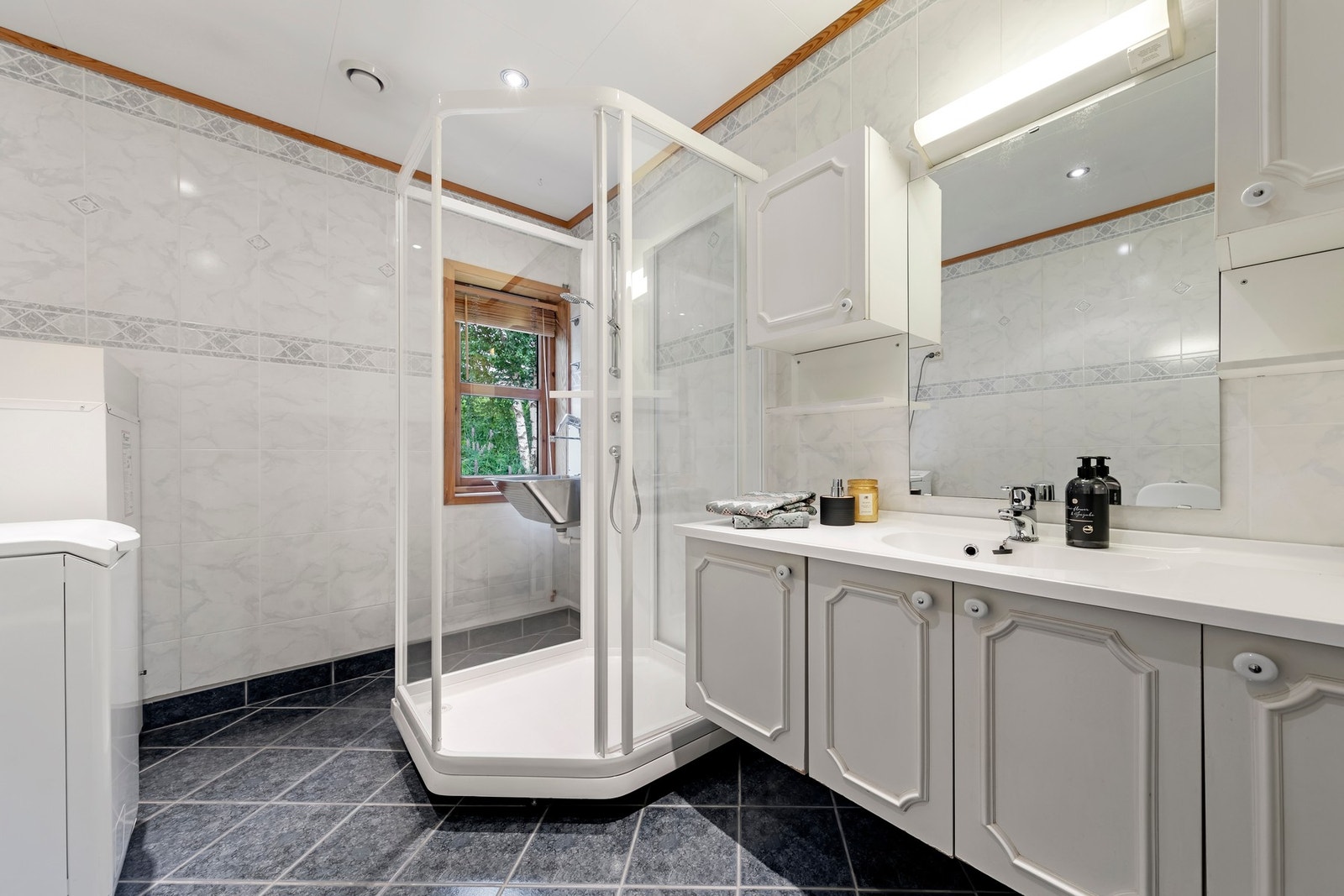 Stort bad med mye lagring, gulvvarme og opplegg for vaskemaskin. Galleribilde