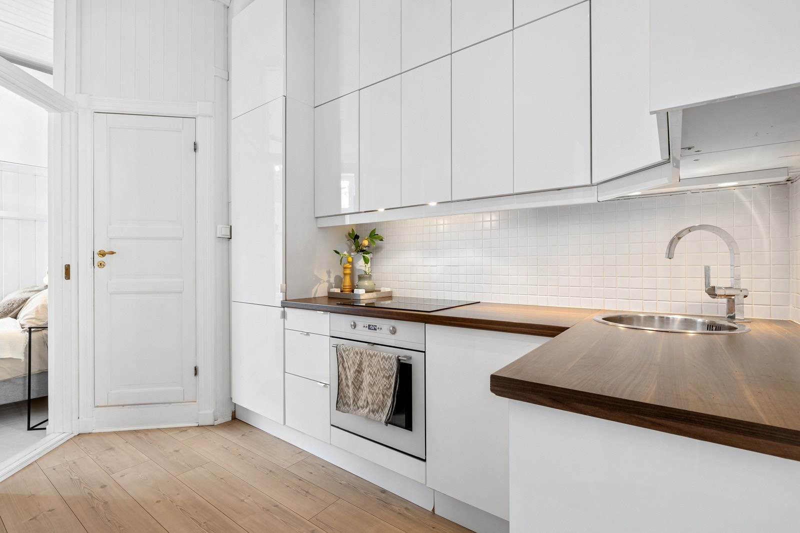 Kjøkkeninnredning fra 2010/11 med laminerte benkeplater, flislagt backsplash og slette fronter. Ventilator med kullfilter, med utkast i overskapet Galleribilde