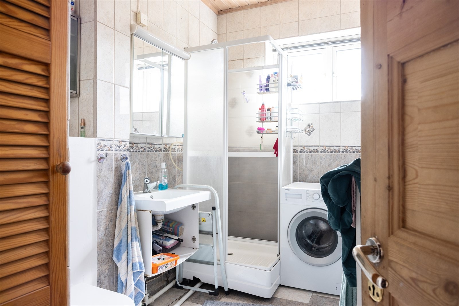 Flislagt bad med vindu og opplegg for vaskemaskin. Galleribilde