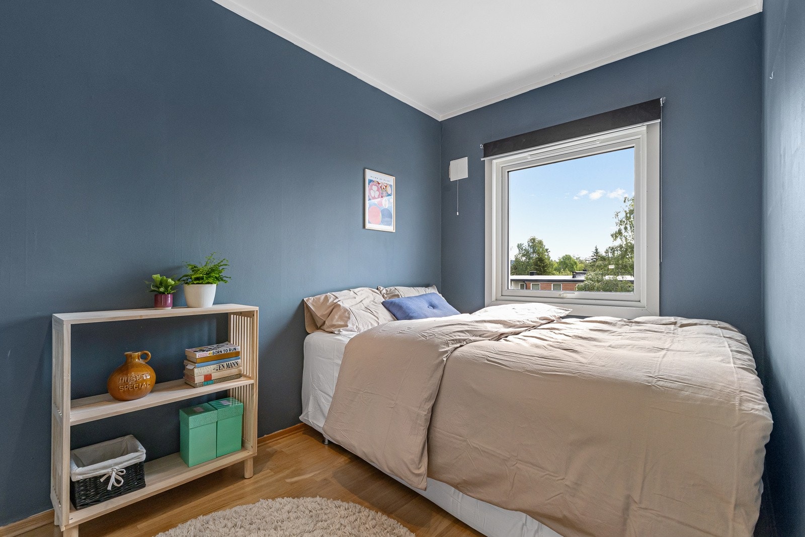 Leiligheten har ett soverom med parkett på gulvet og malte overflater i moderne fargevalg. Galleribilde
