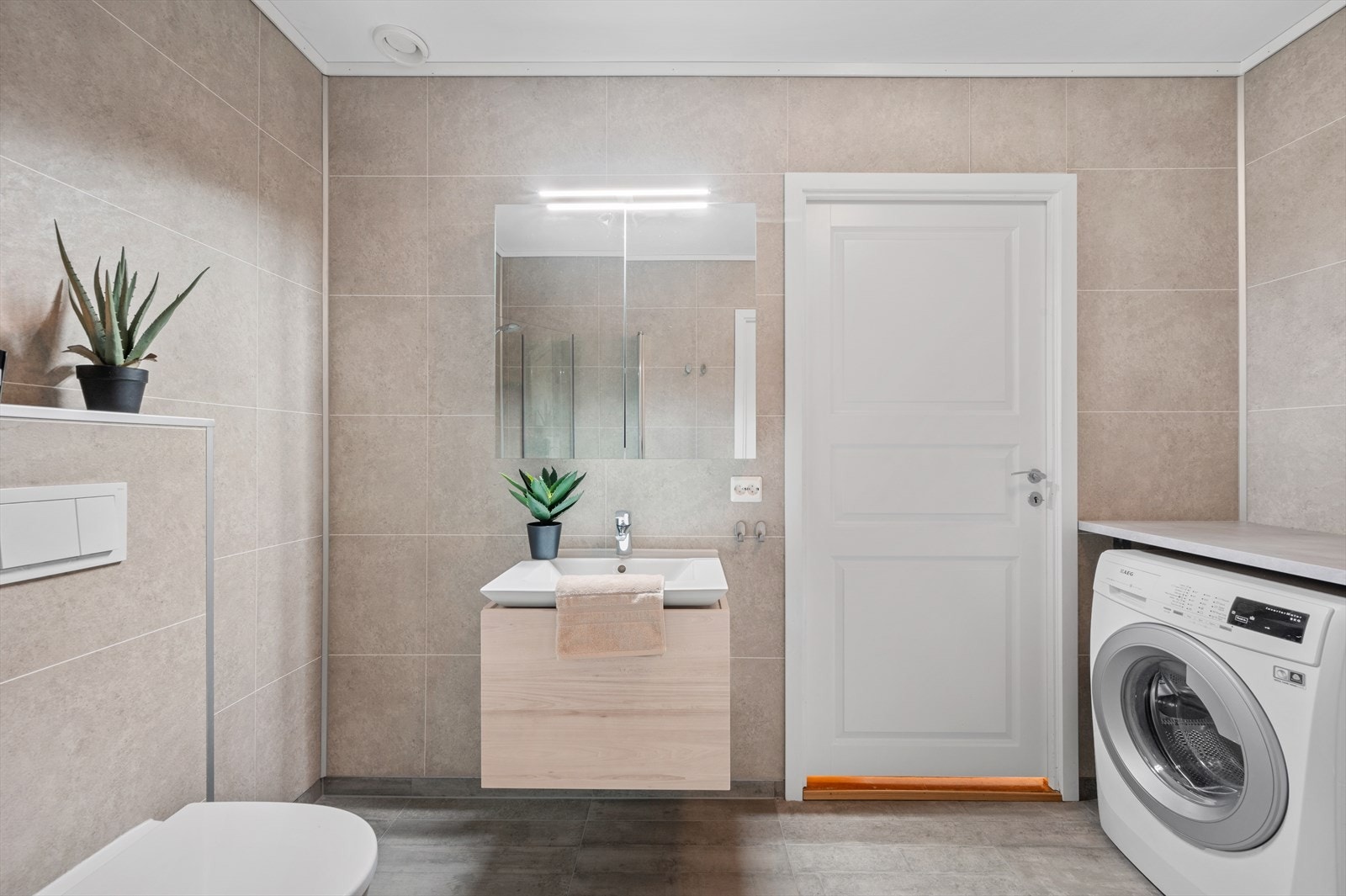 - Badet inneholder vegghengt toalett, benkeskap med servant, dusjdører i glass og skapinnredning - Galleribilde