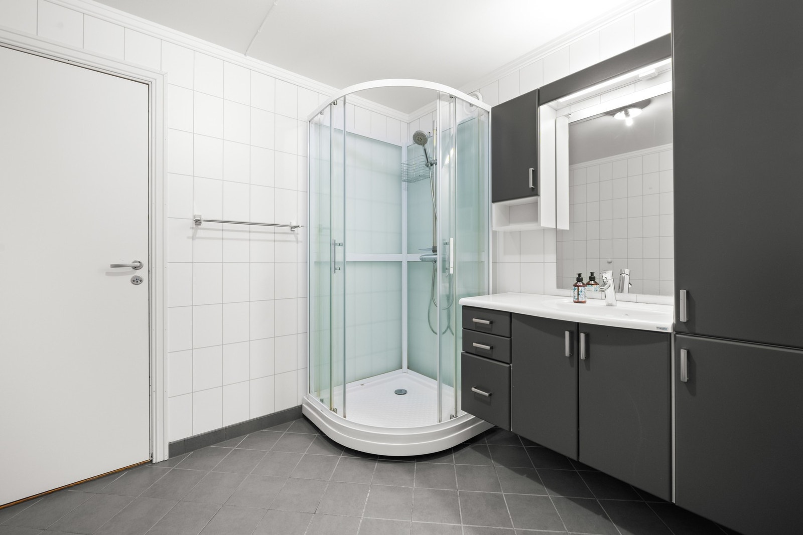 Badet er innredet med en moderne baderomsinnredning med glatte fronter, heldekkende servant, speilskap med overliggende belysning og dusjkabinett. Badet har opplegg for vaskemaskin. Galleribilde