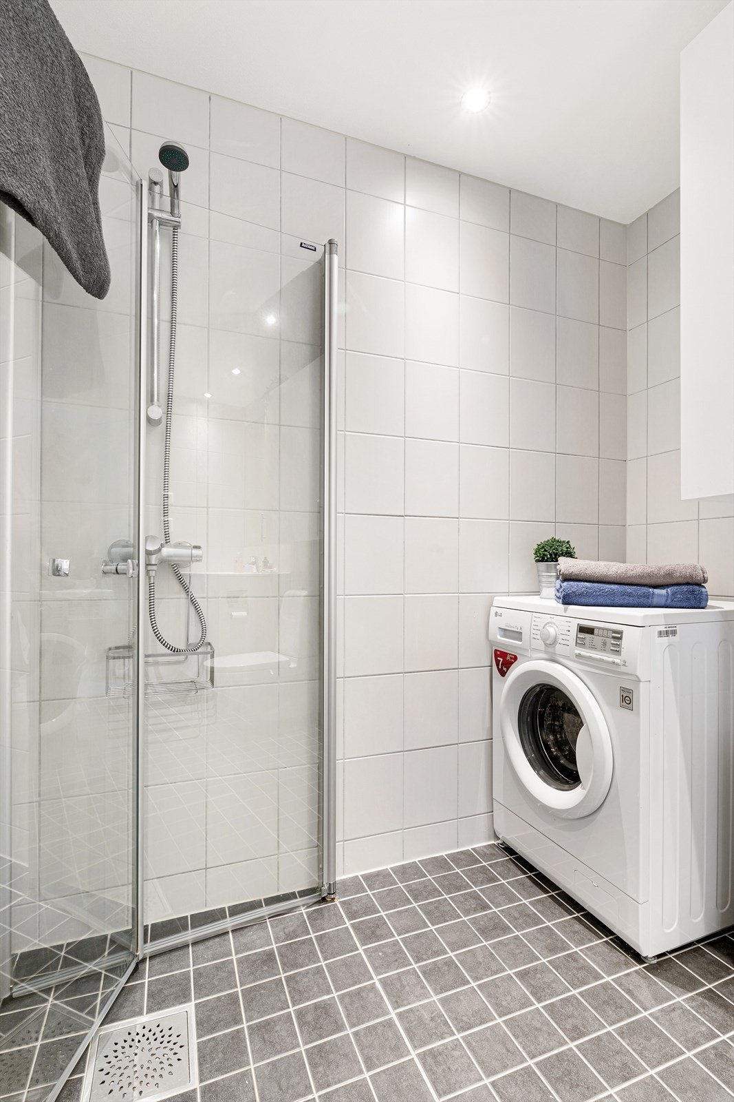 Her får dere alt dere trenger med veggmonterte dusjdører, servant med underskap, speil, overskap, opplegg for vaskemaskin og veggmontert wc. Dette er et herlig sted å starte dagen! Galleribilde