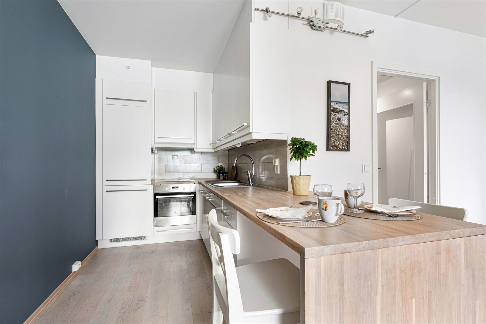 Kjøkkenet fra Atlas er plassert i hjørne av rommet. Innredningen består av hvite fronter og heltre, nyslipt benkeplate. Galleribilde