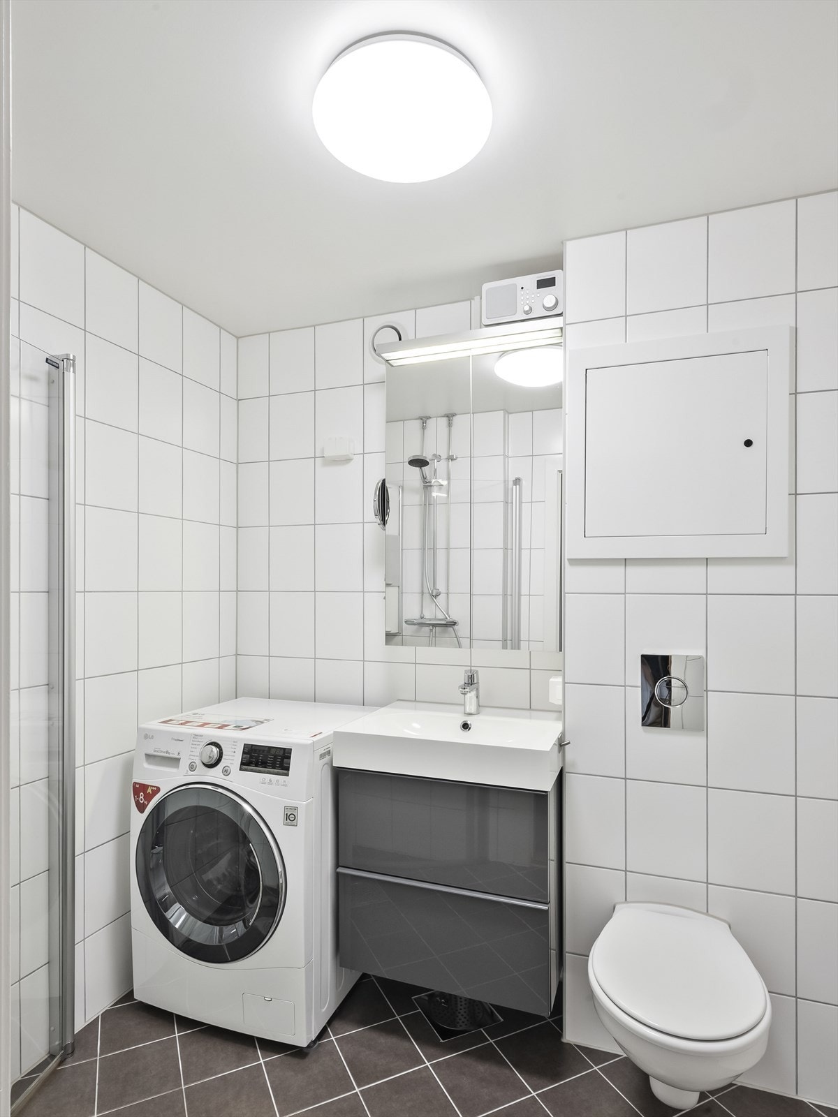 Innredningen består av vegghengt wc, dusjhjørne med hengslede dører og servant med underskap, overskap med speilfronter og overlys samt varmekabler i gulv og opplegg for vaskemaskin. Galleribilde