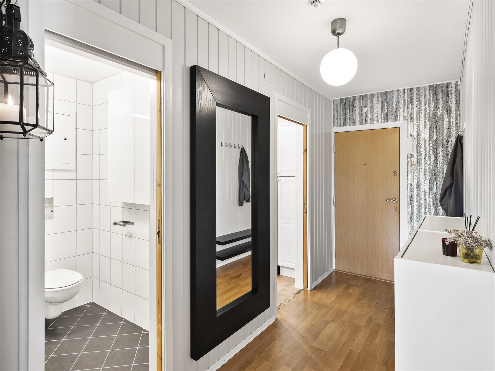 Romslig og trivelig entré med parkett på gulv, tapet og malt panel på vegger og malt tak. Ytterdør som er lyd- og brannklassifisert og det er montert dørcallinganlegg slik at man enkelt kan slippe inn gjester. Galleribilde