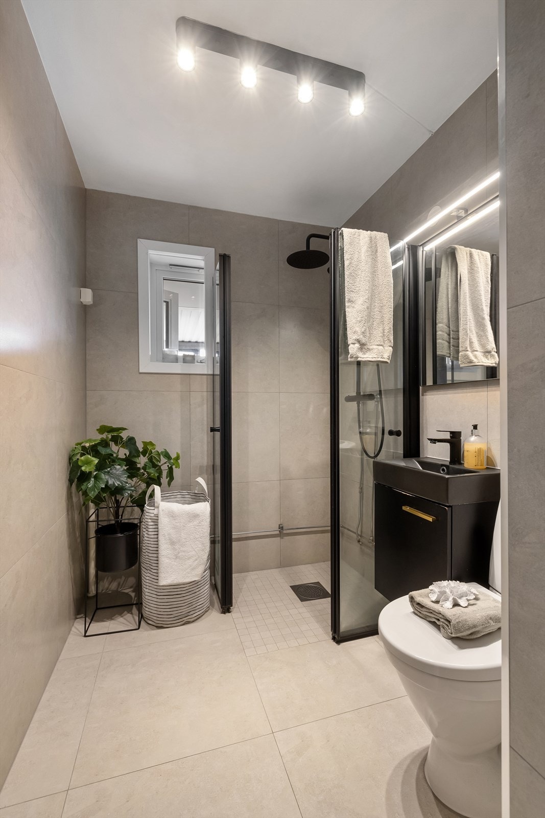 Videre har badet dusjhjørne med svingbare dører i glass og klosett. Det er opplegg for vaskemaskin. Galleribilde