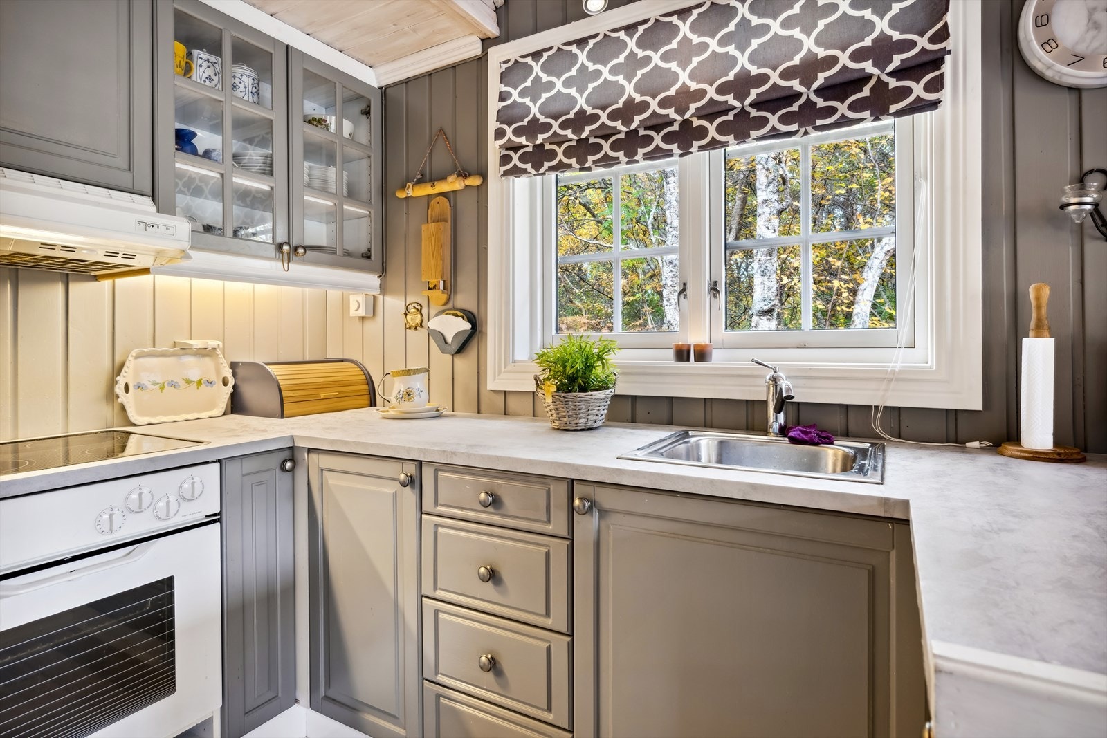 Innredningen består av grå profilerte fronter med enkelte vitrinedører samt integrert komfyr og platetopp. Galleribilde