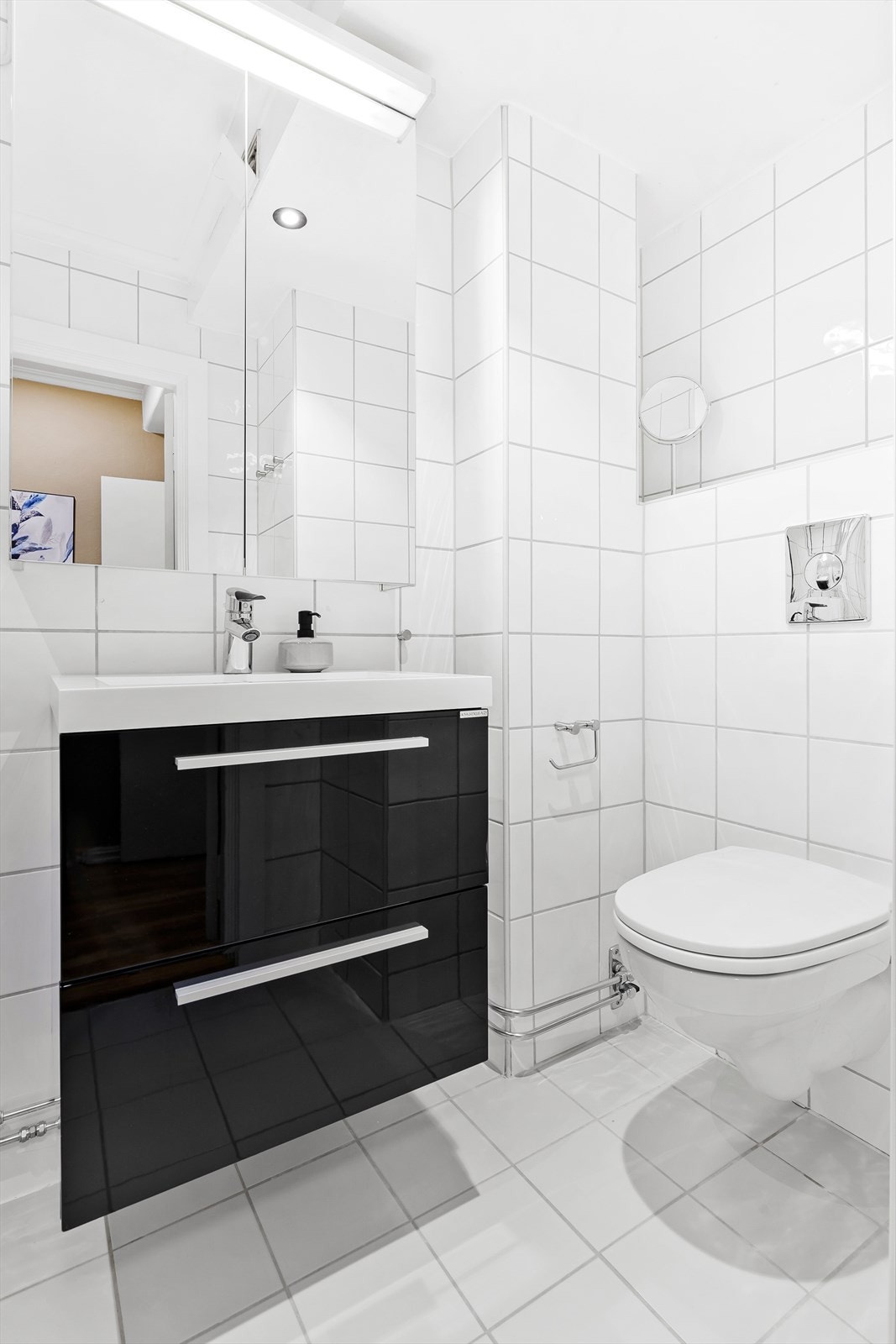 Badets innredning består av servant med underskuffer, speilskap, opplegg til vaske -og tørkemaskin samt dusjhjørne med innfellbare dører. Galleribilde