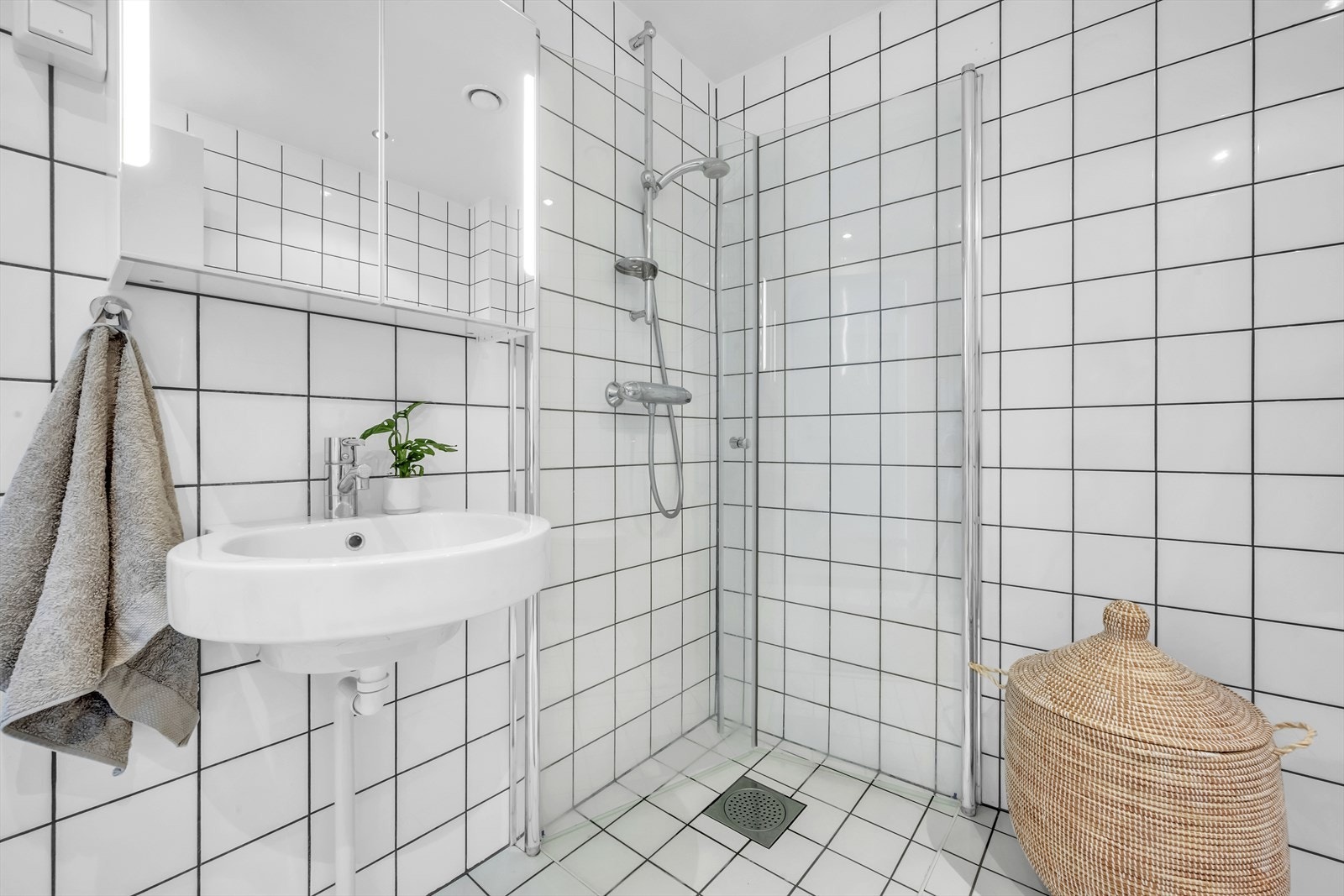 Baderomsinnredning med servant, overskap med rom for oppbevaring og dusjsone. Galleribilde