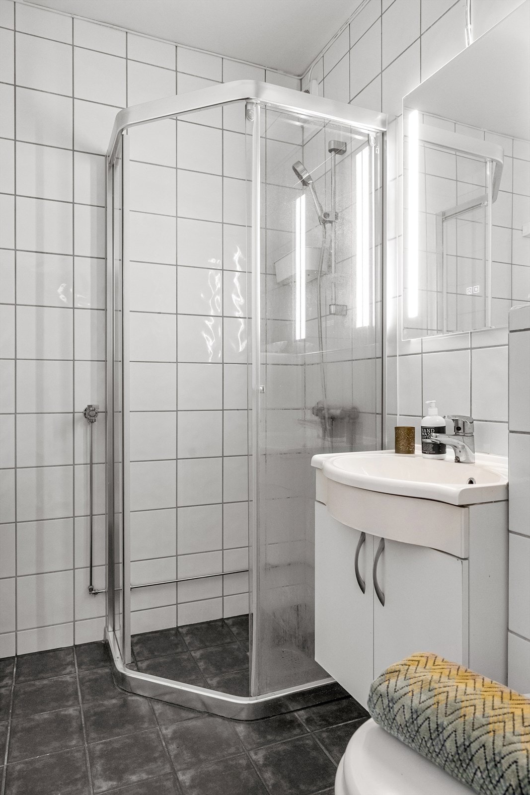 Videre har badet dusjhjørne med innfellbare dører i glass og vegghengt toalett. Det er opplegg for vaskemaskin. Galleribilde