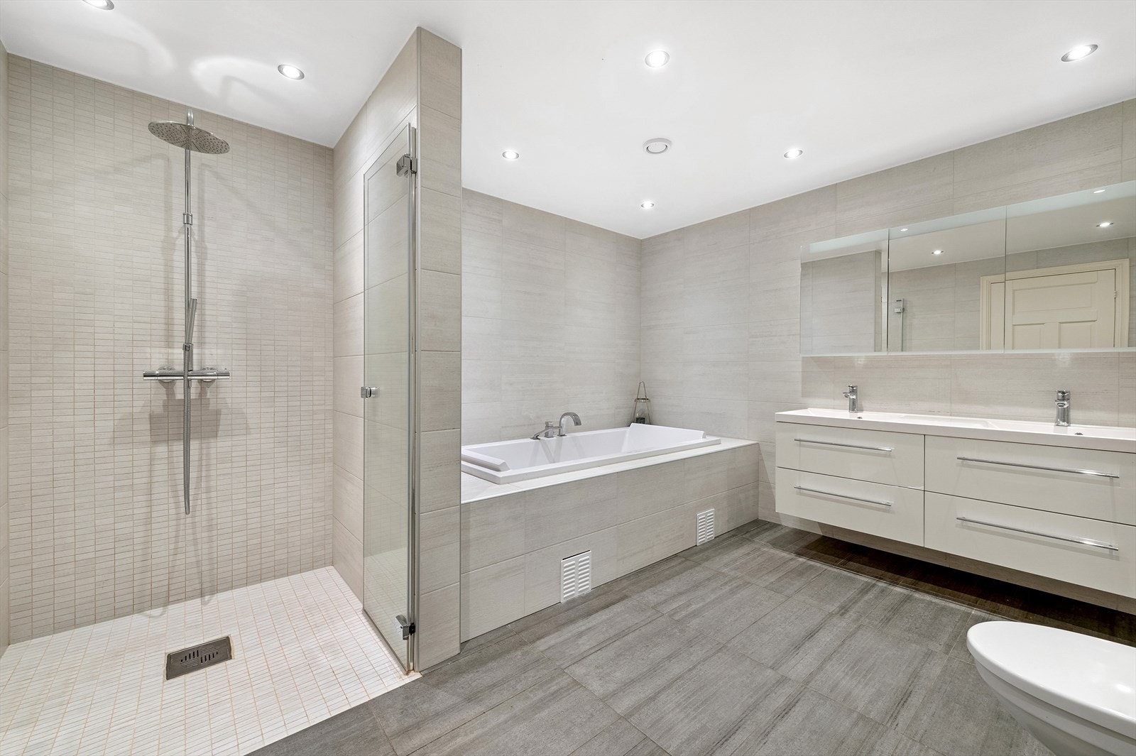 Moderne bad fra 2014 med flislagt gulv, downlights, integrert badekar, regndusj og dobbelvask Galleribilde