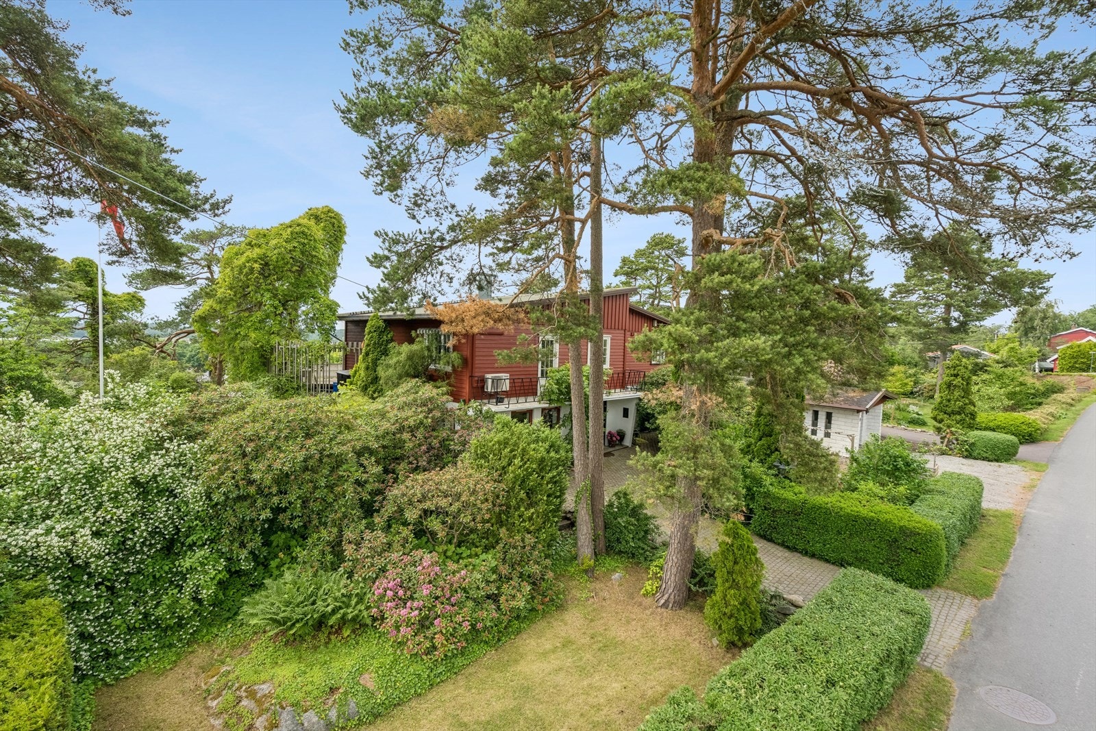 Den store tomten har hekk ut mot gaten og rikelig med trær og diverse beplanting. Galleribilde