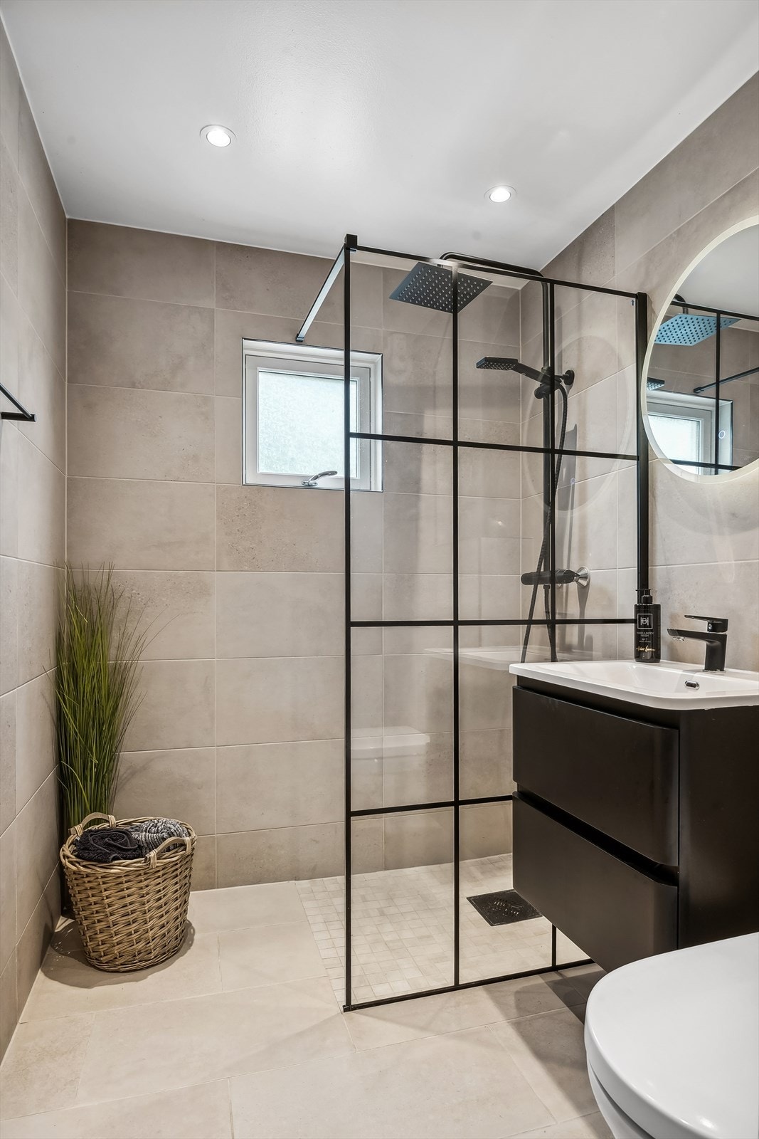 Badet har servantseksjon med skuffer, speil med integrert lys og nedsenket dusjhjørne med skillevegg i herdet glass. Ellers har badet vegghengt toalett og fuktavstyrt avtrekksvifte. Galleribilde