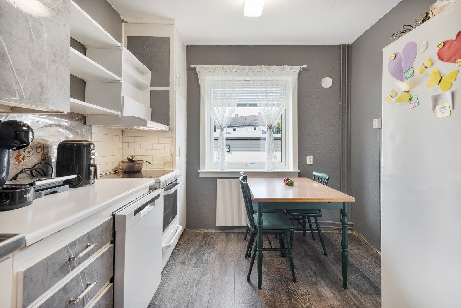 Innredningen har takhøye overskap med slette, folierte fronter, laminatbenkeplate og heldekkende stålbeslag med oppvaskkum. Galleribilde