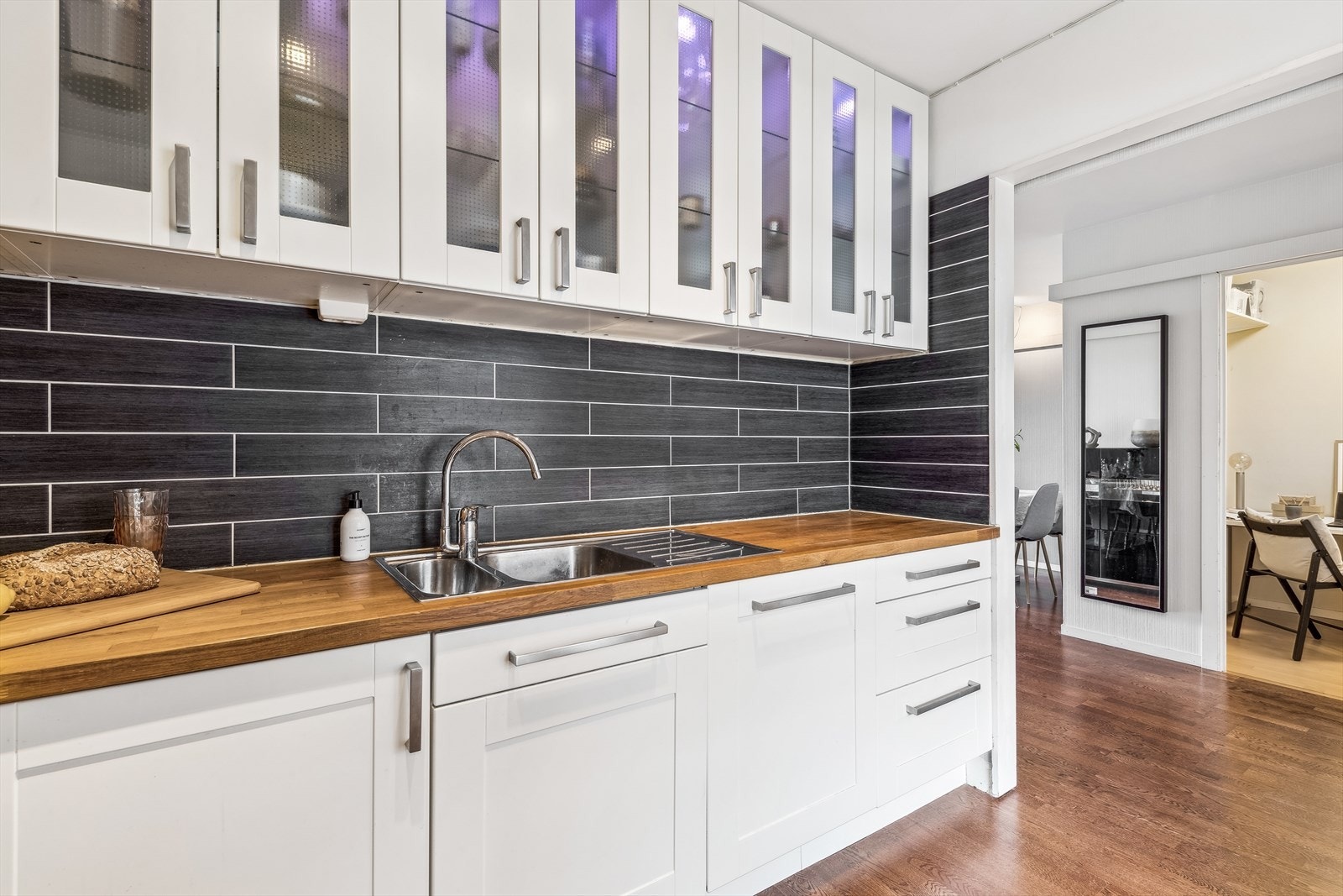 Kjøkkeninnredning i hvit utførelse med benkeplate av heltre eik med nedfelt kjøkkenkum i stål og et greps blandebatteri. Kjøkkenet er levert av IKEA og er nytt fra 2011. Galleribilde