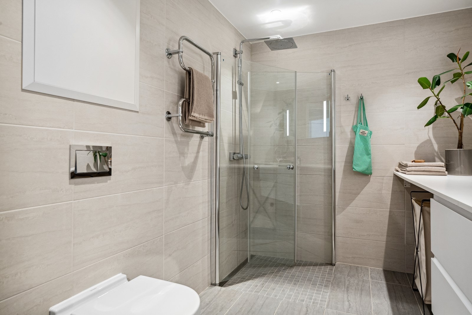 Badet er lekkert innredet med downlights, regnfallsdusj og store, grå fliser for et gjennomført uttrykk. Galleribilde