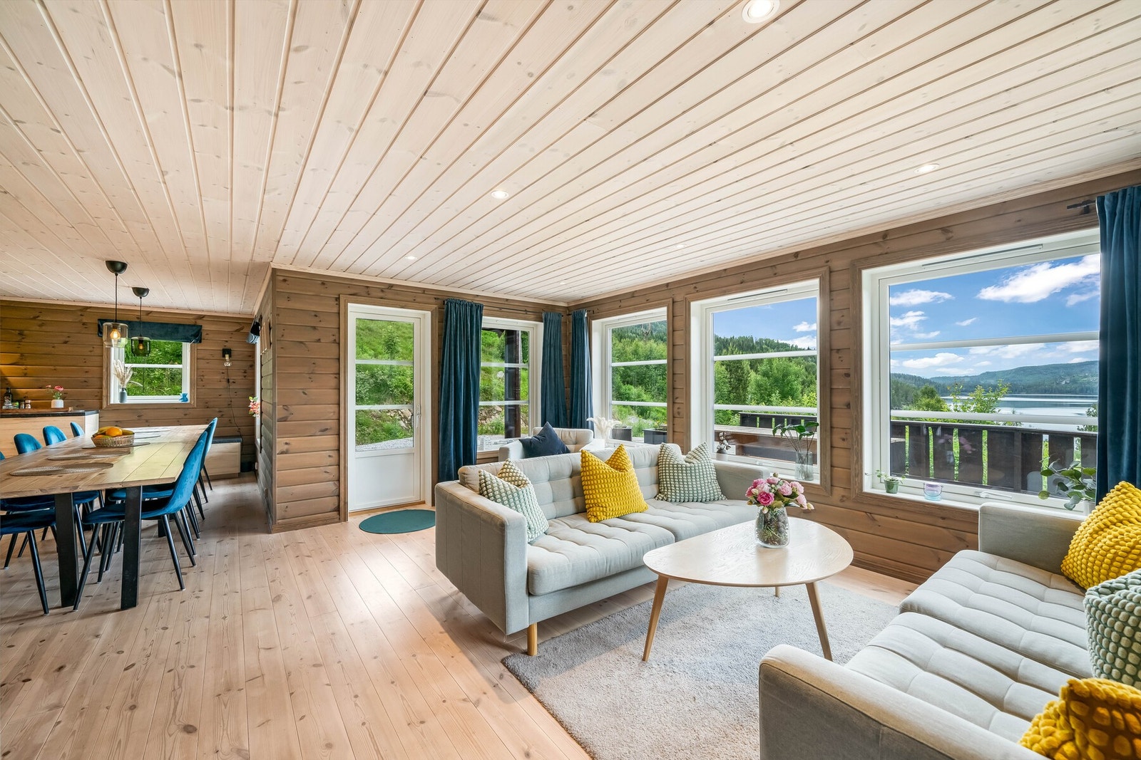 Stor og åpen stue med store vindusflater som sørger for rikelig med lys og flott utsikt. Det er åpen løsning mellom stue og kjøkken, noe som sørger for en luftig atmosfære. Galleribilde