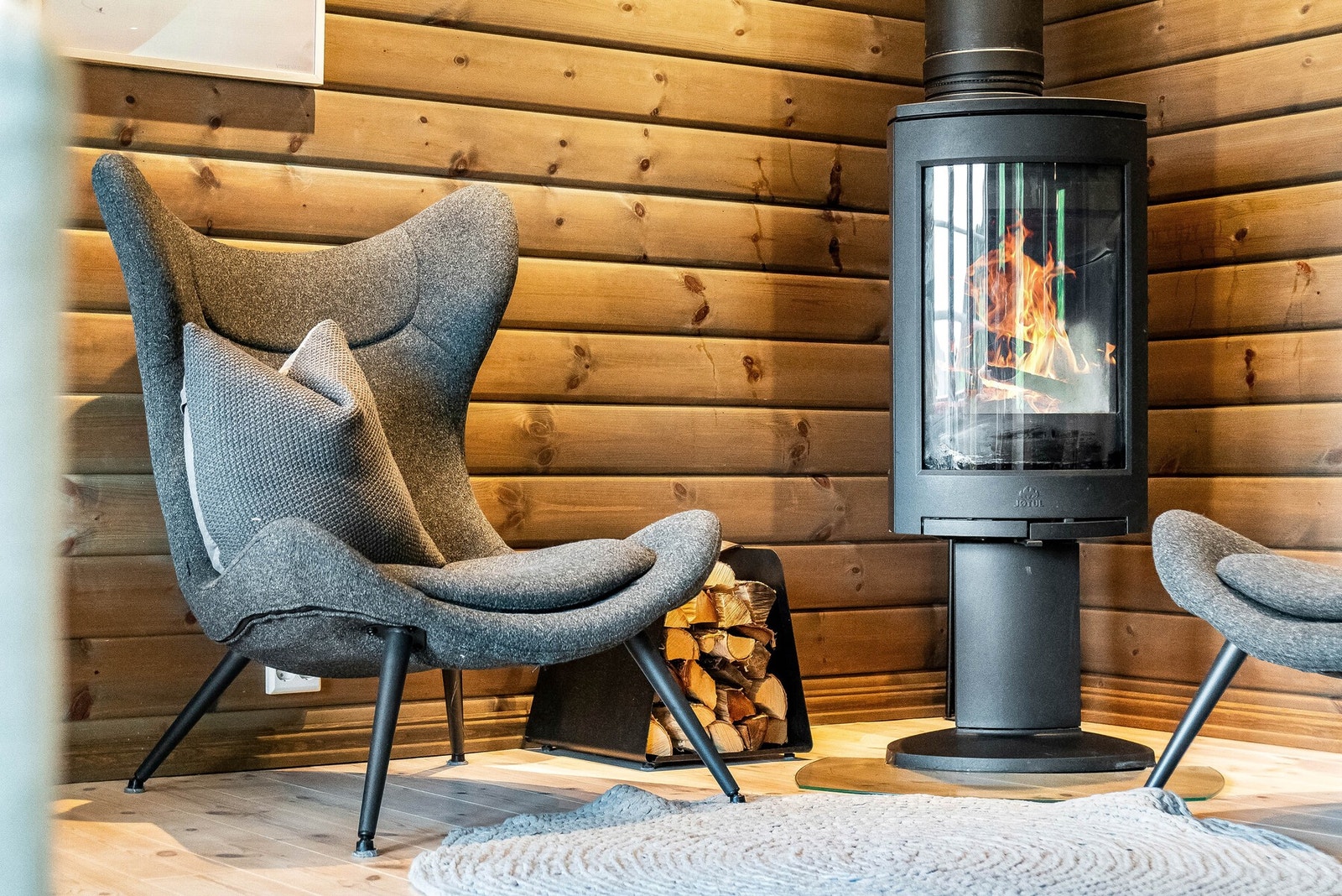 Stua er utstyrt med peisovn med stort glassfelt som varmer godt på kalde dager. Her er det i dag møblert til en hyggelig lesekrok. Galleribilde