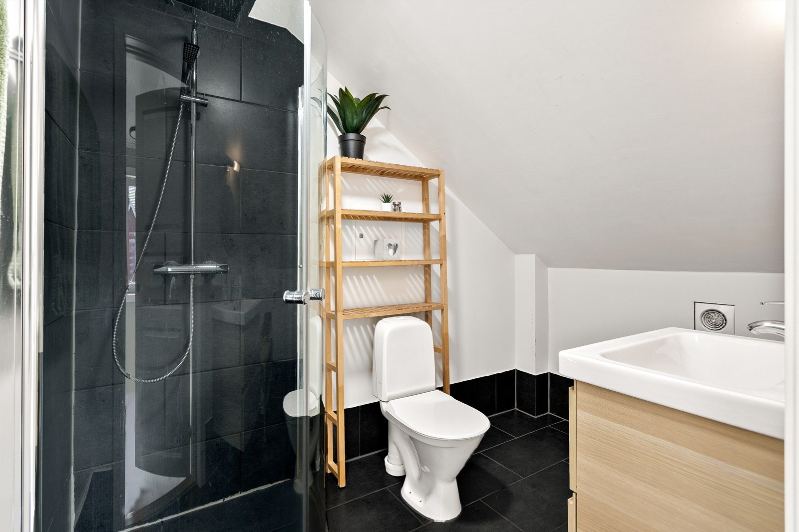 Badet i 2. etasje har flislagt gulv og vegger i selve dusjsonen. Tak og vegger i resten av baderommet har overmalte plater. Galleribilde