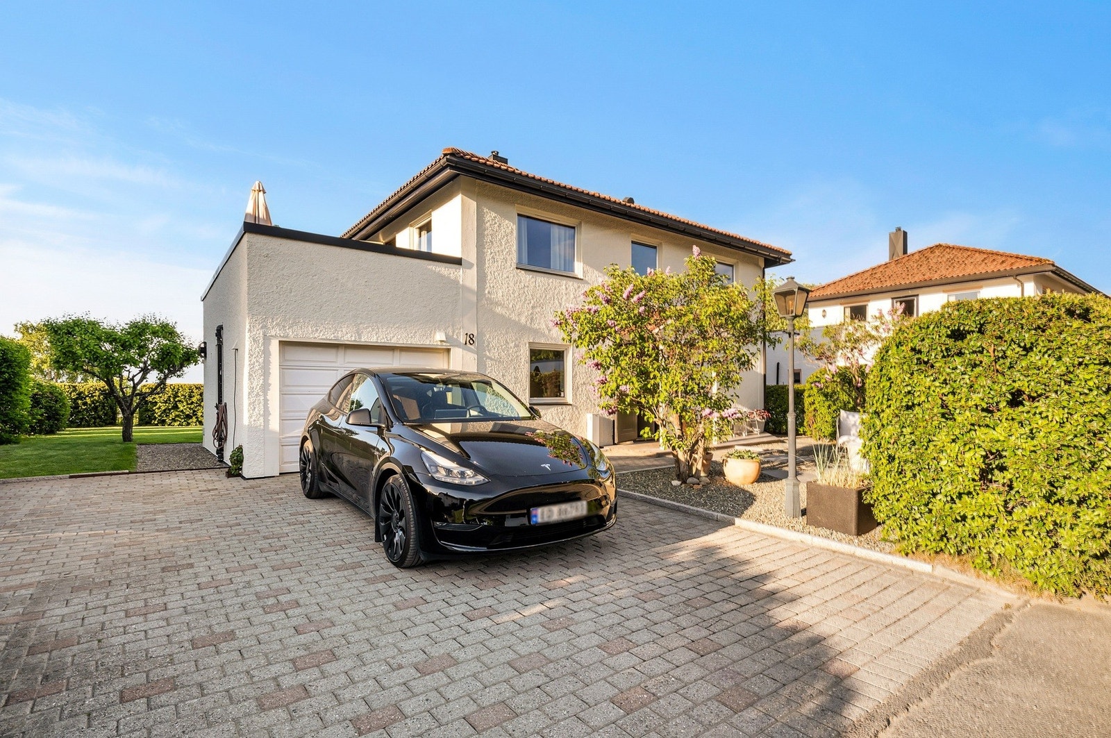 Steinlagt gårdsplass med parkering i garasje og oppstillingsplasser på tomt. Det er installert 32A-lader for elbil. Galleribilde