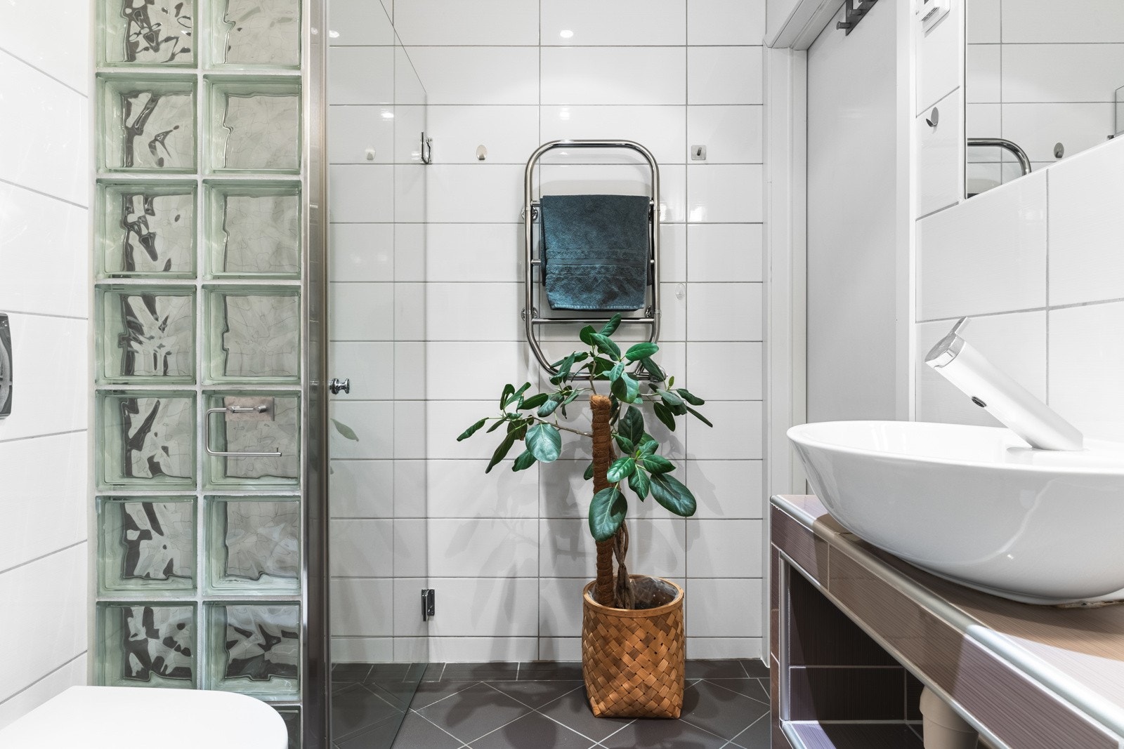 Badet er innredet med plassbygget innredning med dobbel servant, opplegg for vaskemaskin, vegghengt toalett og dusjnisje. Rommet er på 4,6 kvm og har god plass til oppbevaring i skuffer og skap. Galleribilde