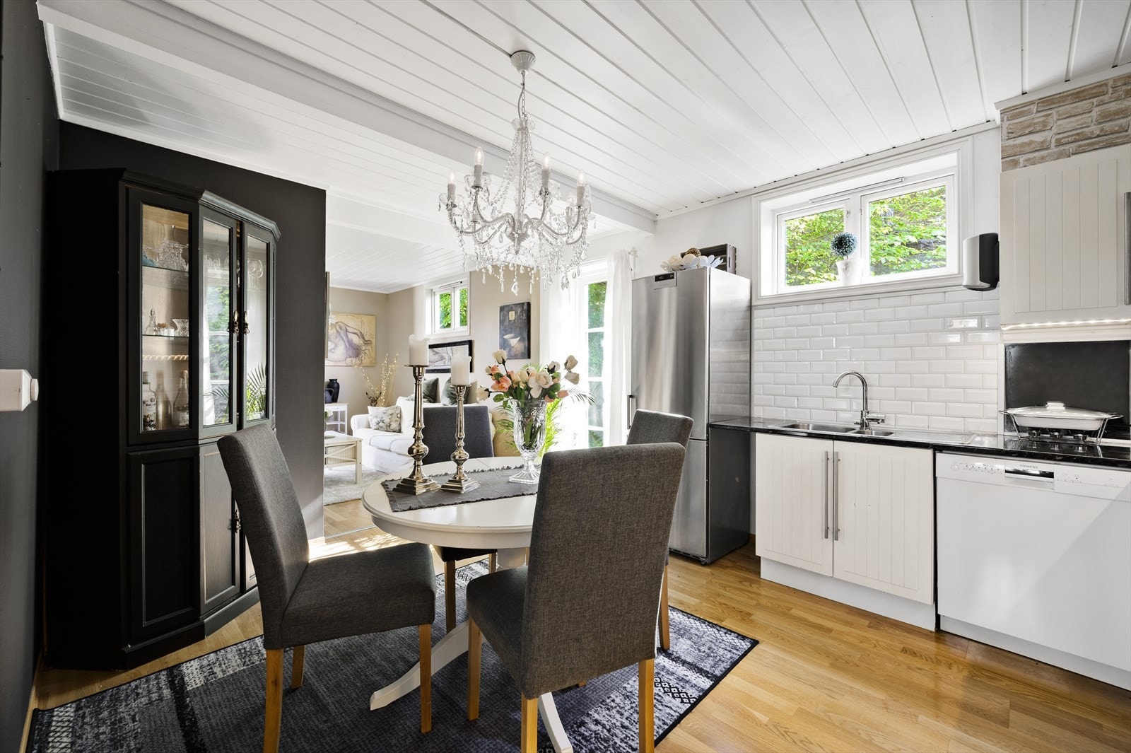 Kjøkkeninnredning fra 2007 med hvite profilerte fronter, laminat benkeplate med nedfelt kum i rustfritt stål, fliser på vegg over benkeskap og belysning under overskap. Galleribilde