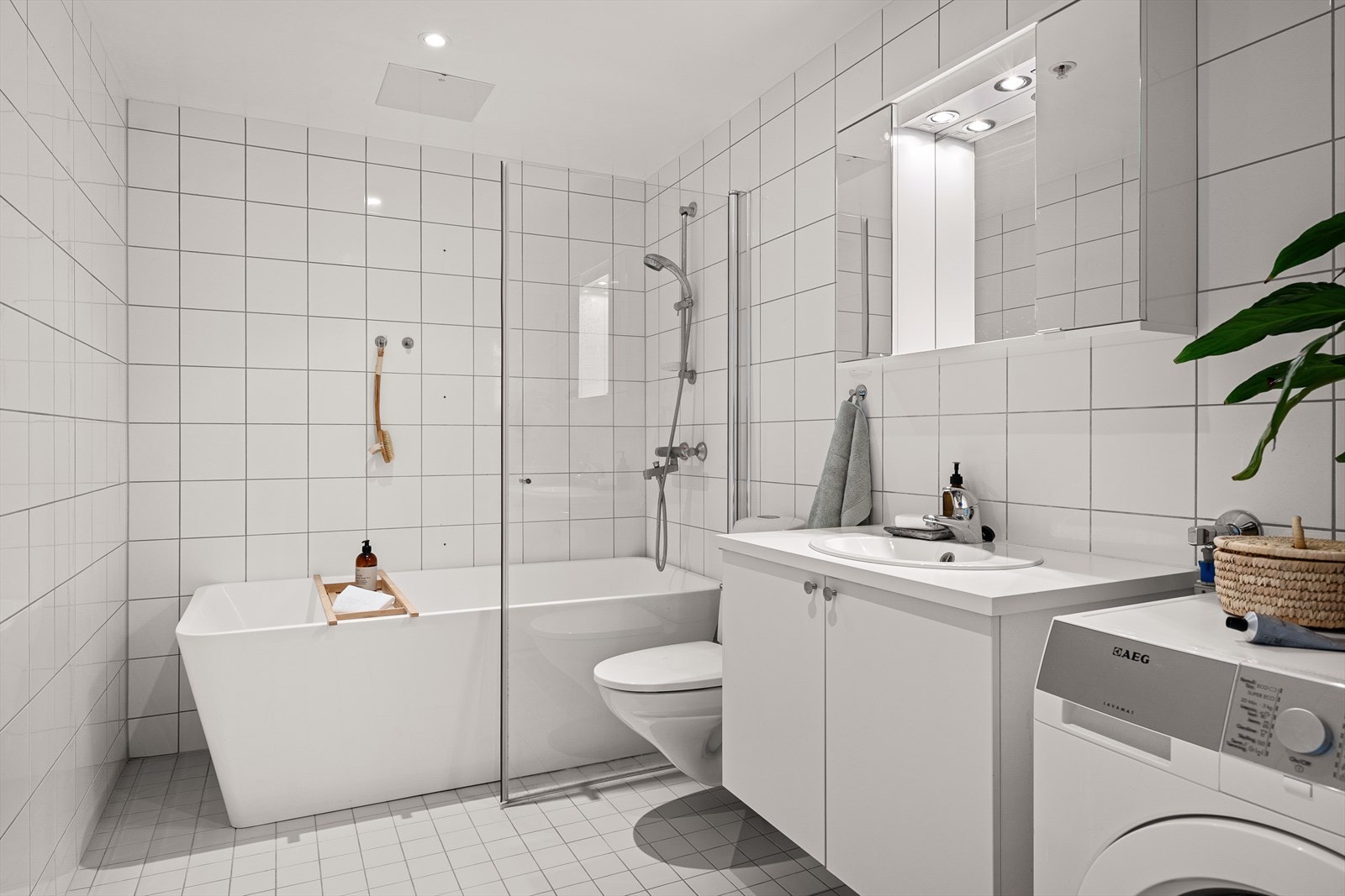 Badet er innredet med vegghengt klosett, servant på innredning og et badekar med dusjarmatur Galleribilde