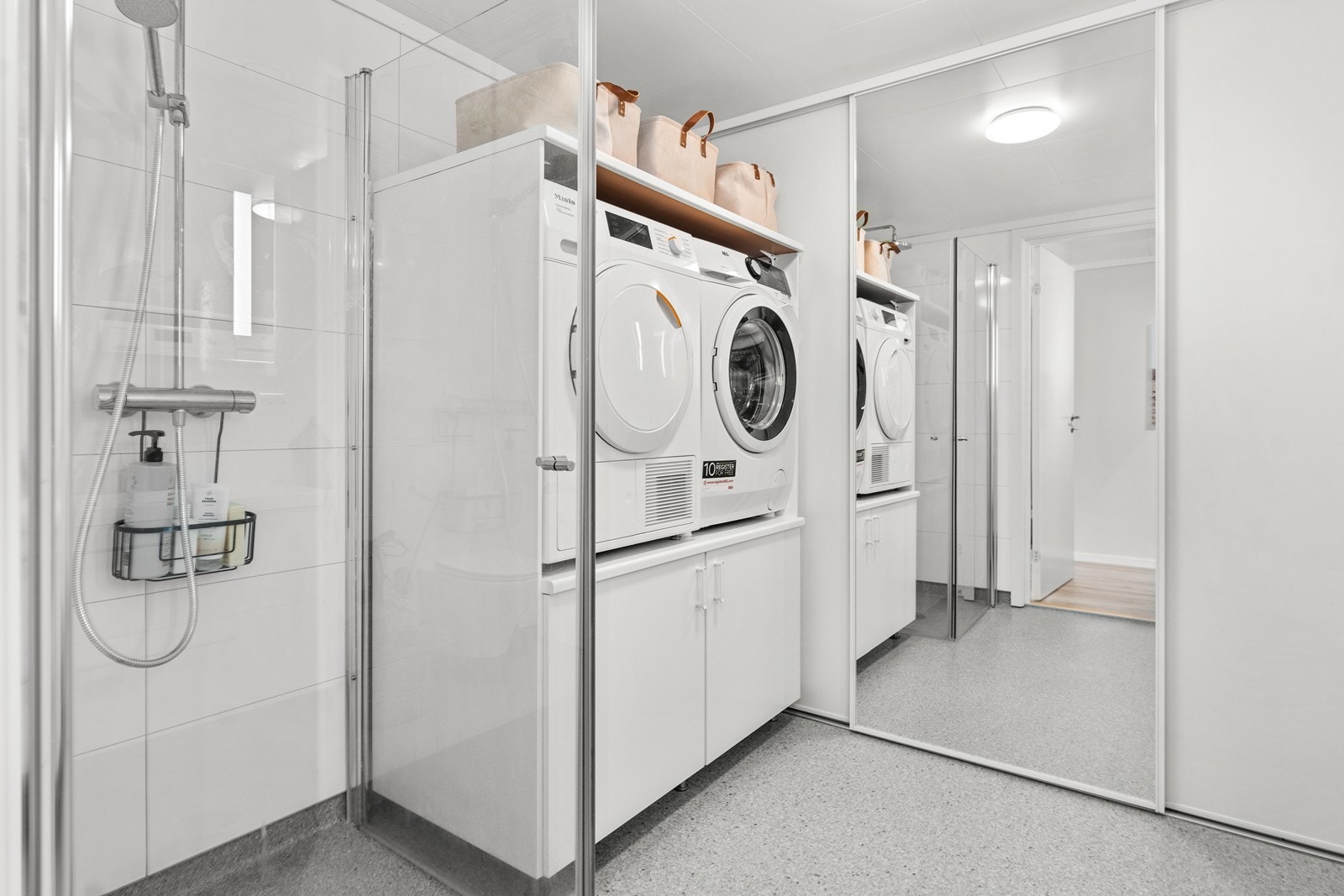 Romslig skyvedørsgarderobe på badet, samt innredning til vaskemaskin og tørketrommel. Galleribilde