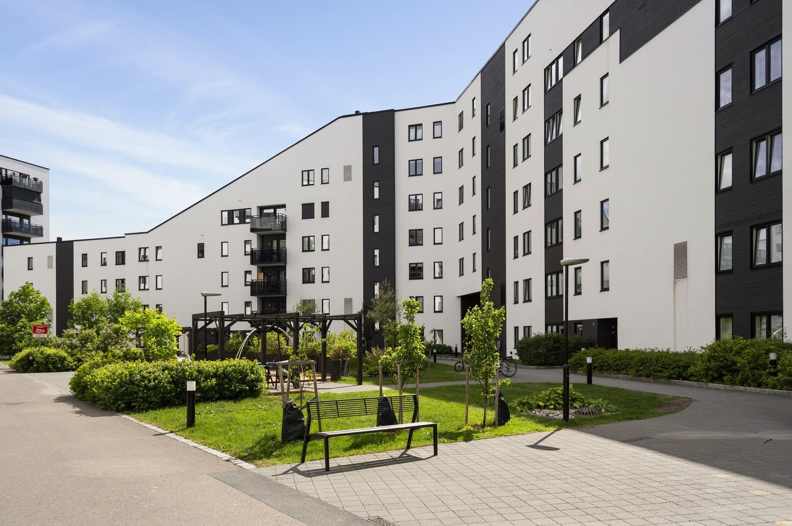 Pent opparbeidet bakgård med plen, diverse beplantning og flere sykkelparkeringer Galleribilde