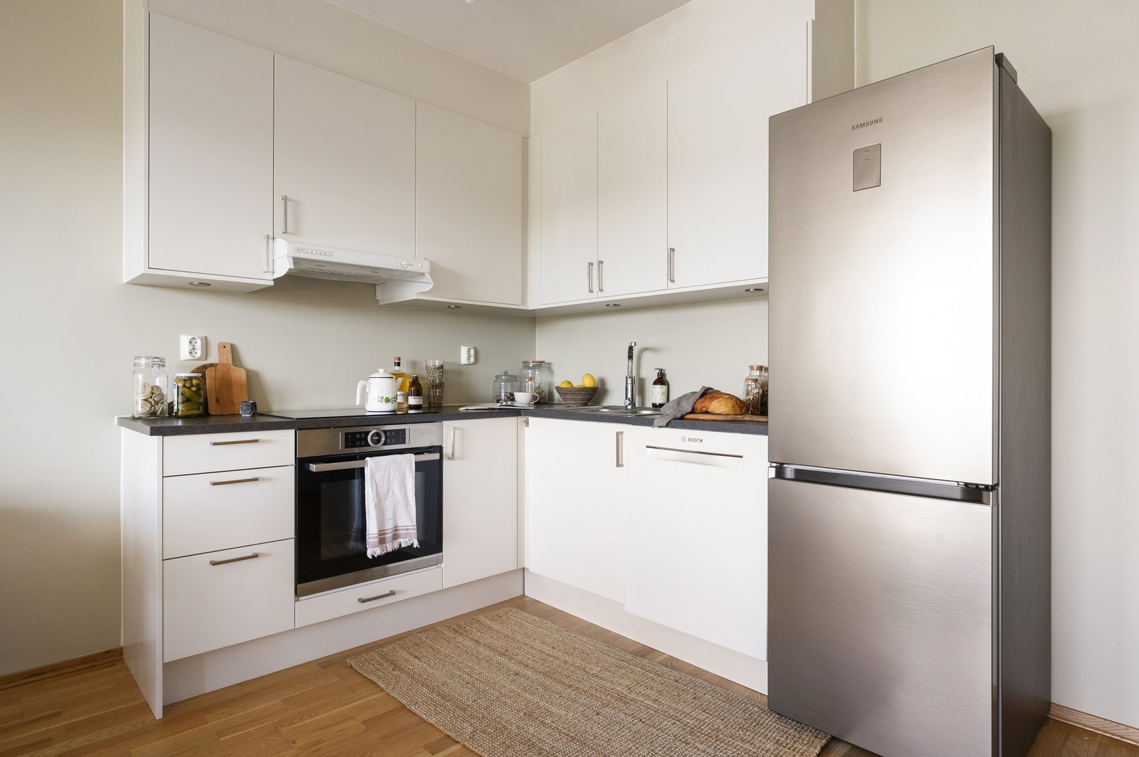 Integrerte hvitevarer som stekeovn med induksjon koketopp og ventilator over -pppvaskmaskin plassert i nisje og frittstående kjøleskap Galleribilde