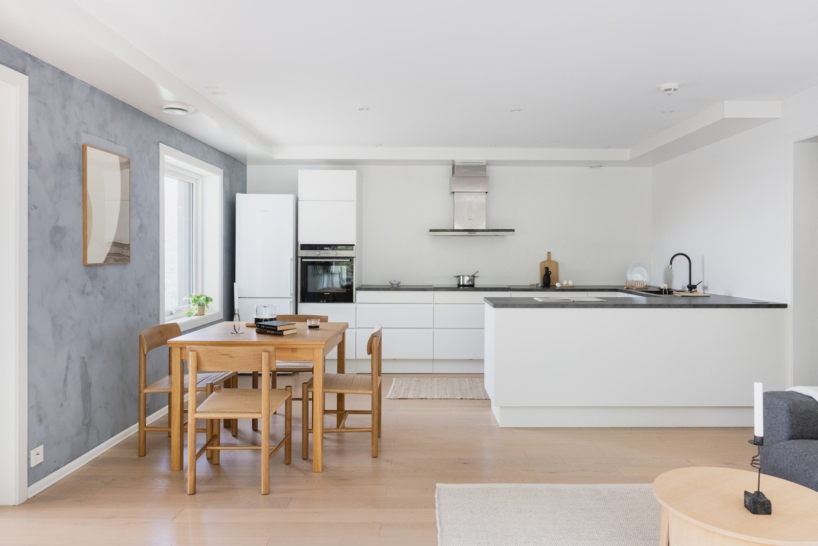 Kjøkkenet består av slette hvite fronter og laminat benkeplate med nedfelt vask av stål. Galleribilde