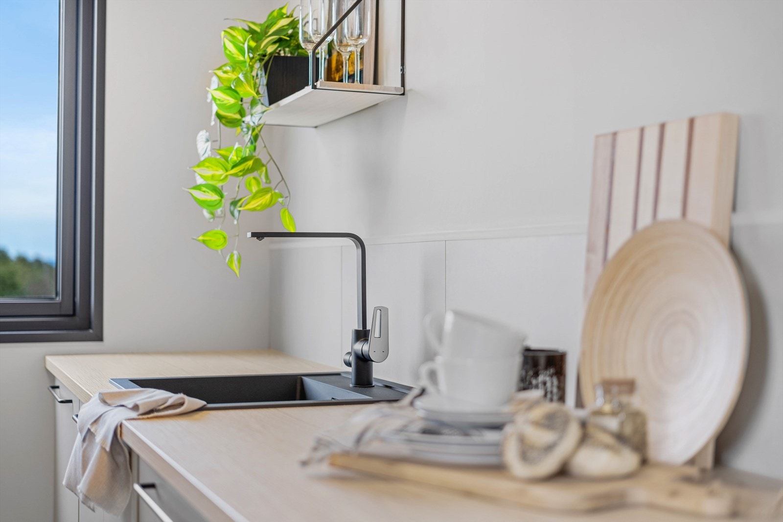 I den lyse laminatbenkeplaten er det en nedfelt, sort oppvaskkum i kompositt. Galleribilde