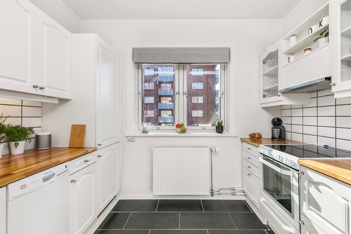 Lyst og elegant, østvendt kjøkken med utsikt inn mot bakgården. Galleribilde