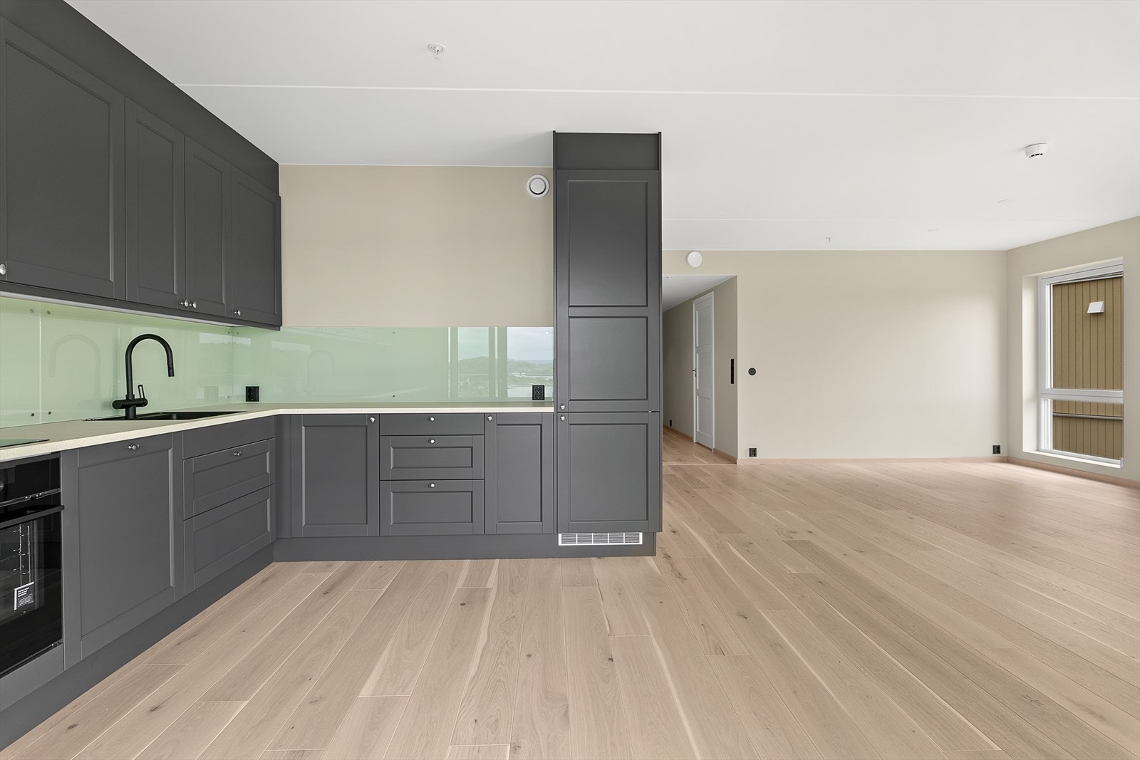 Lekker kjøkkeninnredning med grå, profilerte kjøkkenfronter og laminert benkeplate. Galleribilde