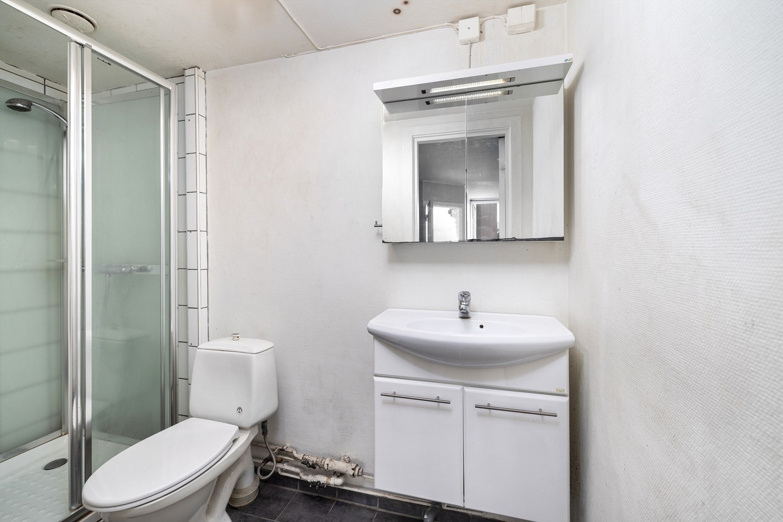 Bad med fliser på gulv, servant innredning, toalett og dusjkabinett Galleribilde