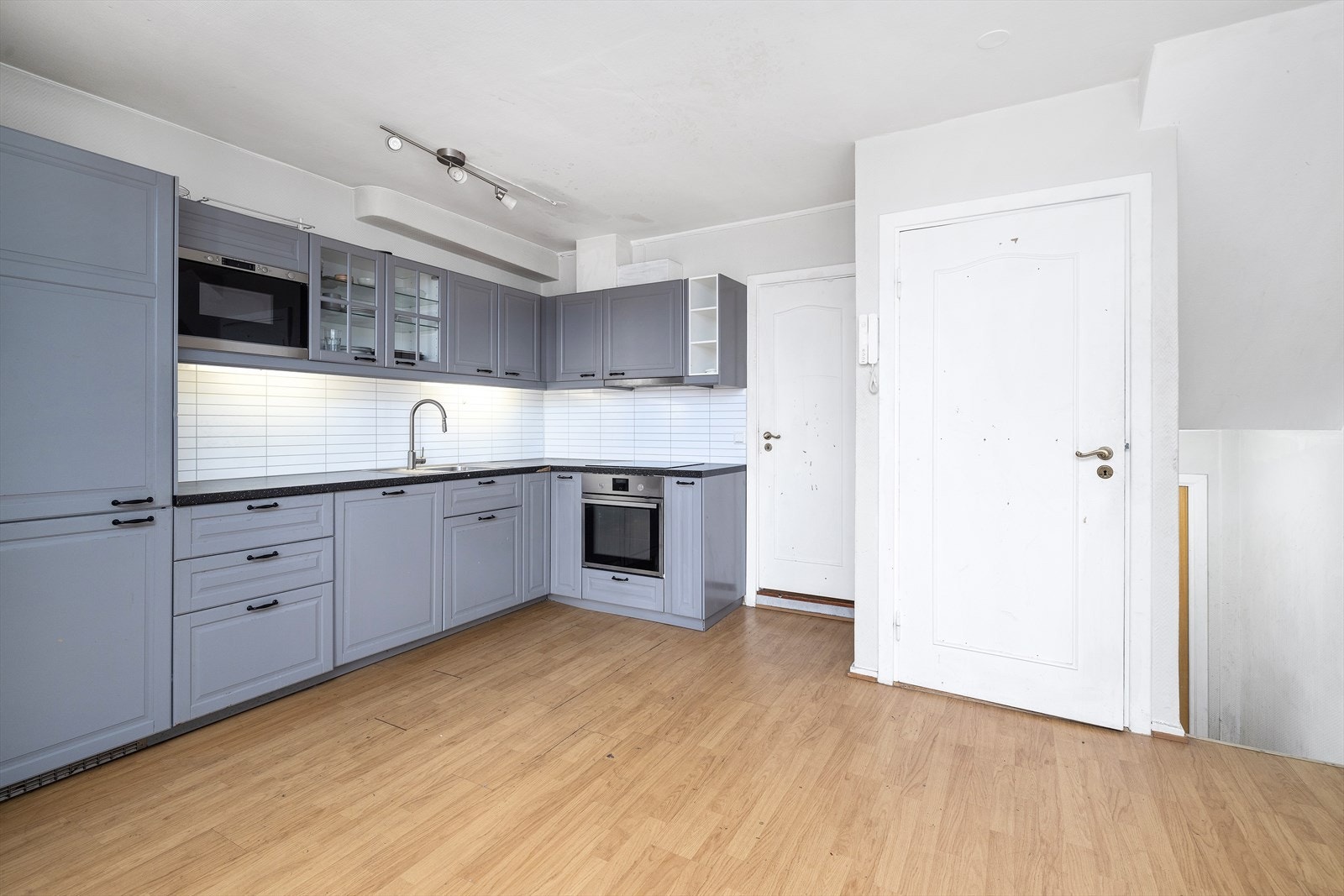 Kjøkken med integrerte hvitevarer som stekeovn, platetopp, vaskemaskin, kjøleskap og mikro Galleribilde