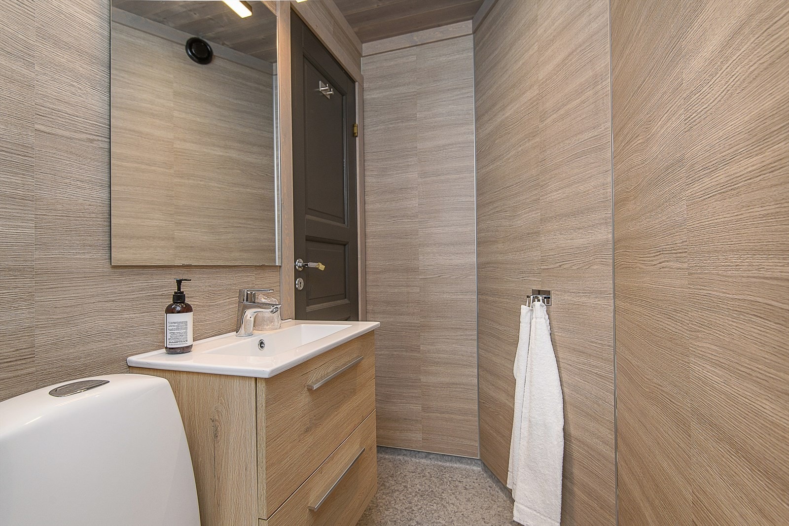 Moderne og flotte baderom med baderomsinnredning med heldekkende servant og skuffer under. Dusj med skyvedører og gulvmontert toalett. Galleribilde